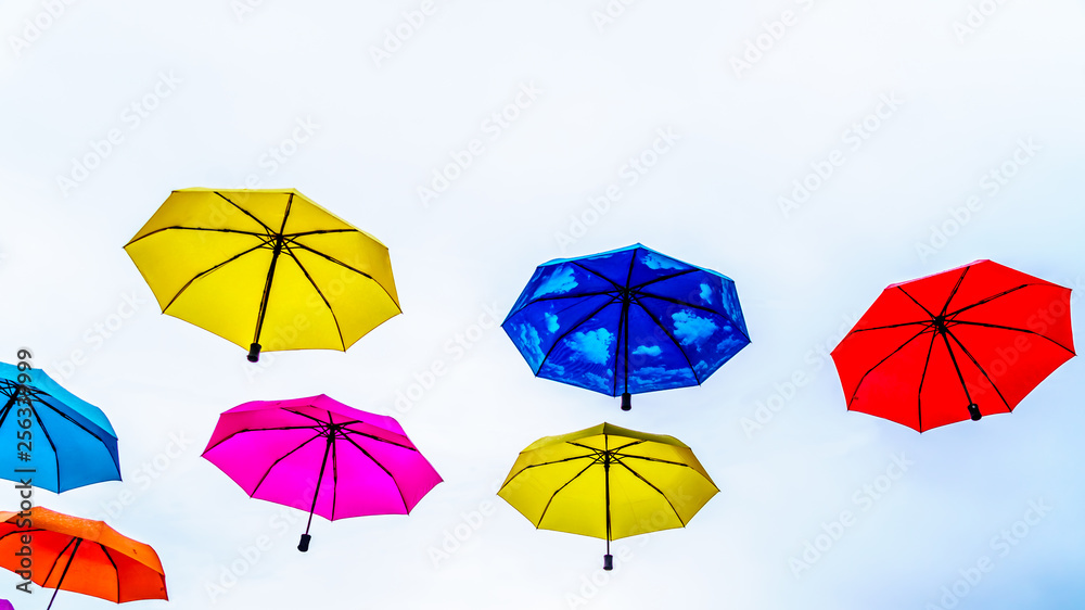 Colorful Umbrellas floating in the air under cloudy sky