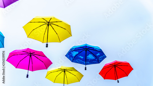 Colorful Umbrellas floating in the air under cloudy sky © hpbfotos