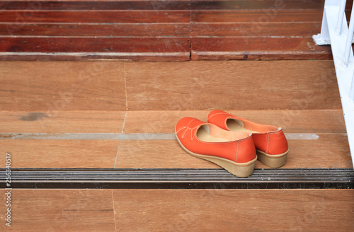 Orange leather female shoes place on wood stair.