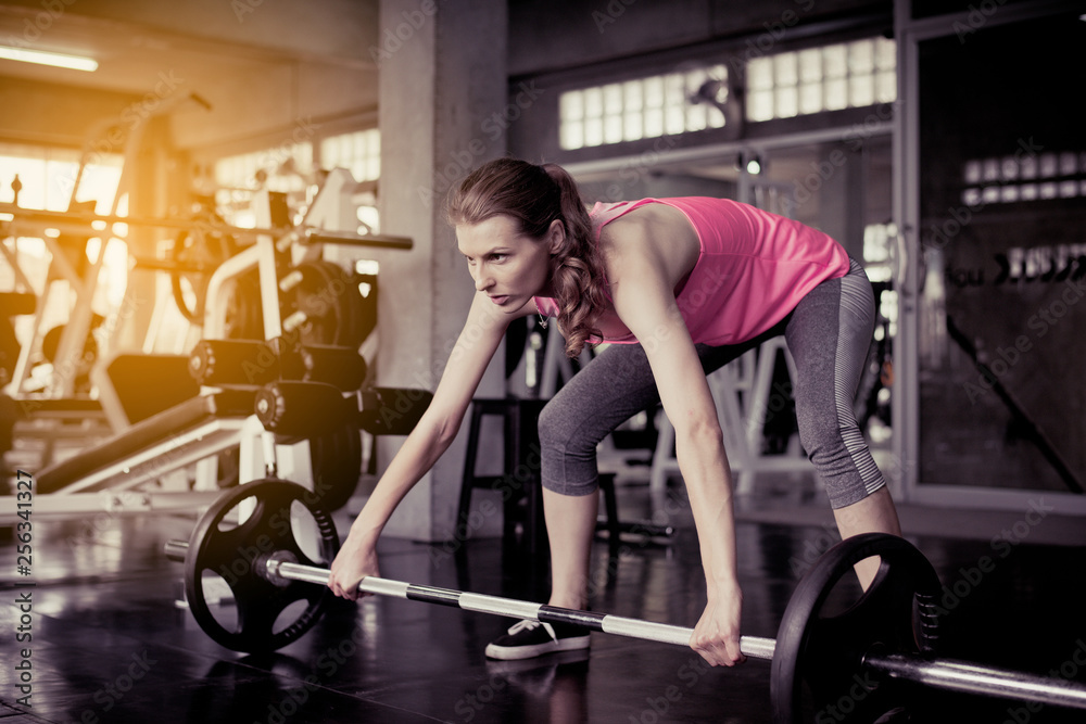 Fototapeta premium Sporty caucasian woman exercise with barbell,Female does the exercising at gym