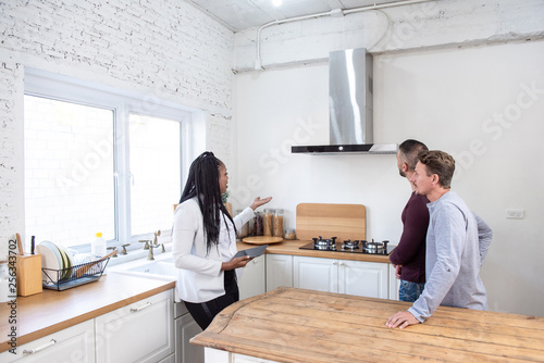 Female real estate agent showing gay couple around new house