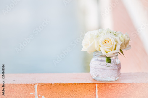 rose in the glass pot on the brick, pastel background