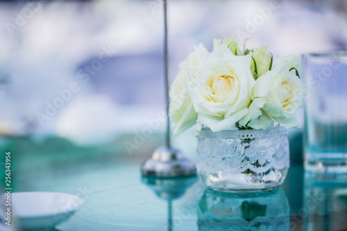 rose in the glass pot on the table, blue pastel background