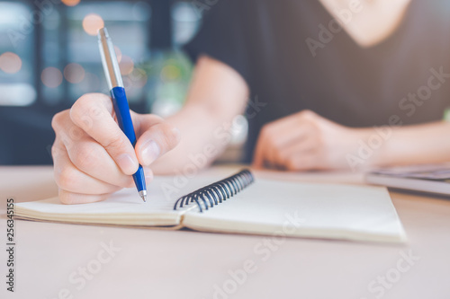 Woman hand is writing on a notebook with a pen.