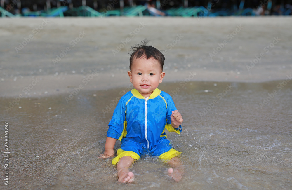 Smiling of little baby boy in swimming suit sitting on the sand beach. Smiling of little baby boy in swimming suit sitting on the sand beach.