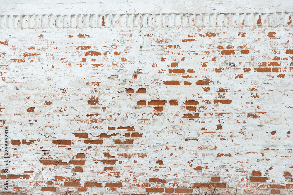 The texture of the old brick wall painted white with peeling paint