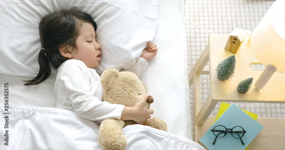 Child girl sleeping with teddy bear on the wooden bed in her bedroom ...