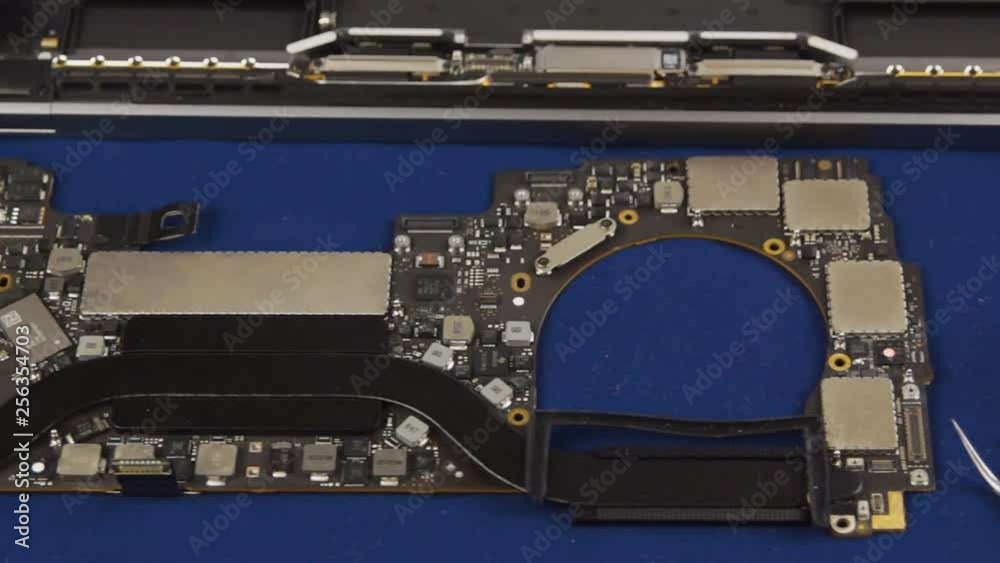 Disassembled laptop. Laptop motherboard next to the case, tools and tester. Close-up
