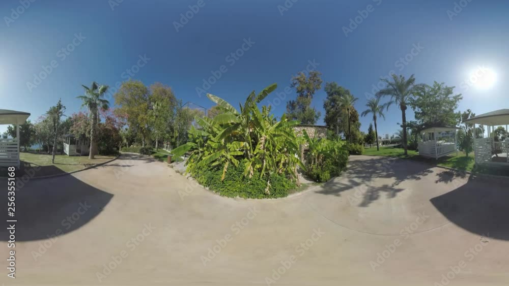 360 VR video. Asphalt paths running across the green area of coastal resort in Turkey, Antalya. View with lovely wooden gazebos on bright sunny day 360 VR video. Asphalt paths running across the green area of coastal resort in Turkey, Antalya. View with lovely wooden gazebos on bright sunny day