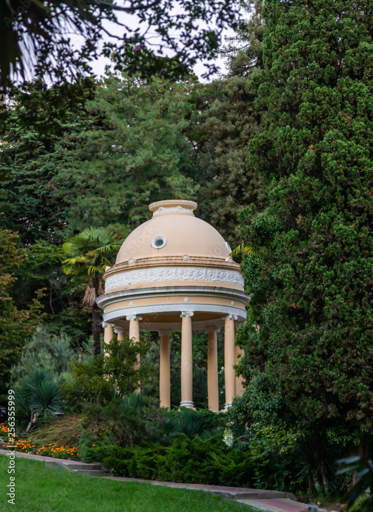 Beautiful beige round arbor with a dome in the Sochi Botanical Garden. Russia