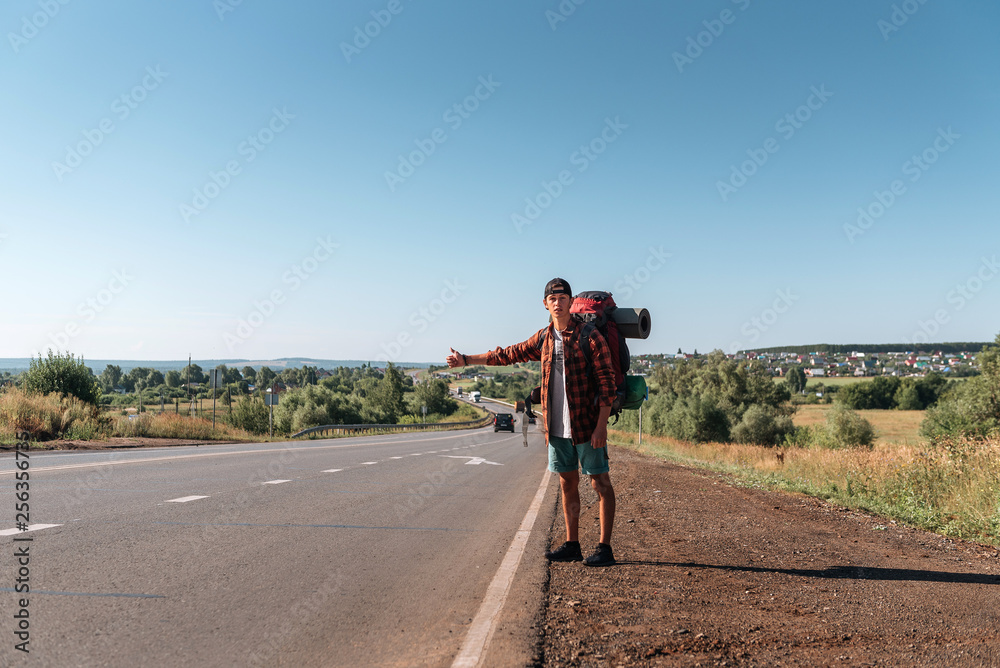 Obraz premium Travel man hitchhiking. Backpacker on road