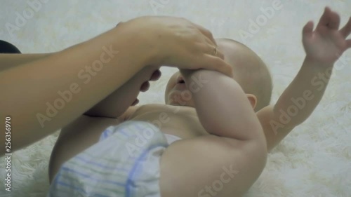 Wallpaper Mural SLOW MOTION: young mother and her six-month-old child together do gymnastics at home on the bed. Torontodigital.ca