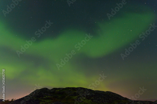 Green northern lights over the hills, aurora. © Moroshka