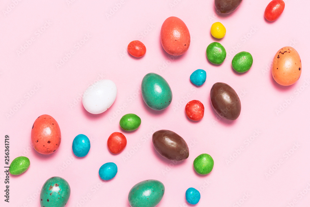 Easter frame made from colorful eggs and big chocolate egg flat lay on white background. Top view, copyspace for text. Easter frame made from colorful eggs and big chocolate egg flat lay on white background. Top view, copyspace for text.
