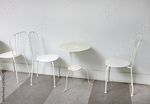 White chairs and table against white wall background.