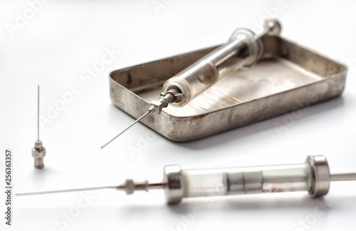 An old glass syringes and a metal box-sterilizer.