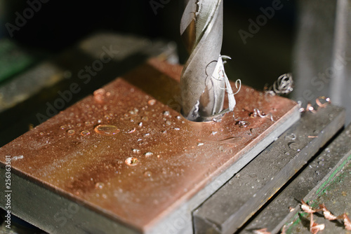 Drilling a hole with a drilling machine in a metal workpiece pulley, close-up, industry, block