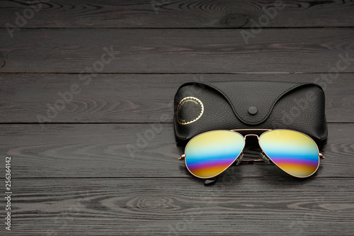 aviators sunglasses with mirrored color lenses made of glass in a gold metal frame covered with gold matte dusting on a black wooden background