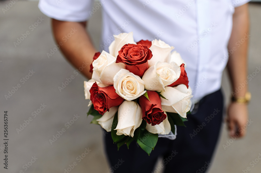 Bridal bouquet of red and white roses in the groom's hand Bridal bouquet of red and white roses in the groom's hand