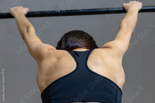 The girl is engaged on the bar in the gym