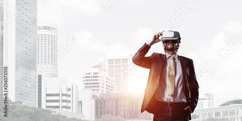 Handsome elegant businessman experiencing impressive virtual reality and business city at backdrop