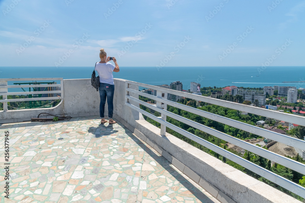 woman photographs on smartphone from viewing platform in Sochi. Russia