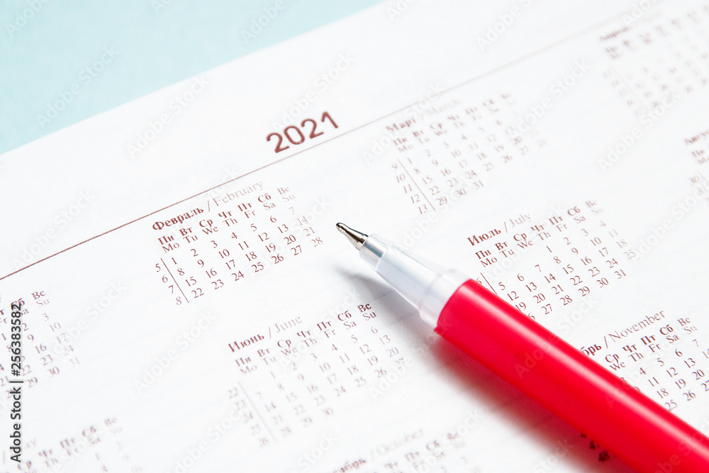 Months and dates shown in calendar in diary and red pen for writing, selective focus Months and dates shown in calendar in diary and red pen for writing, selective focus