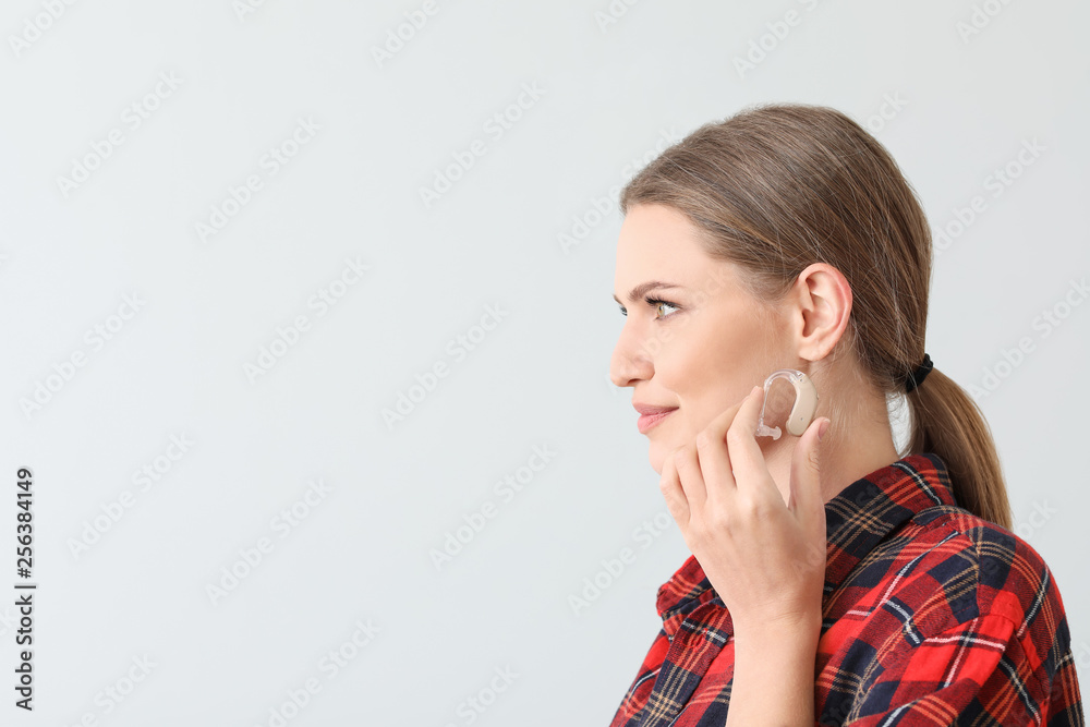 Young woman with hearing aid on light background Young woman with hearing aid on light background