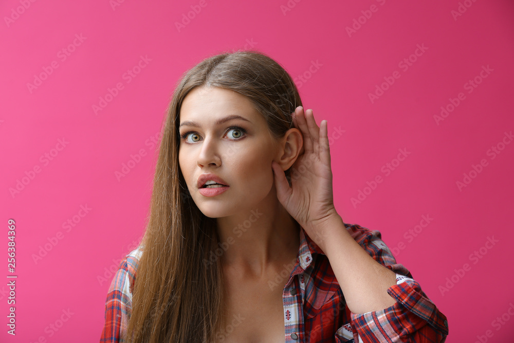 Young woman with hearing problem on color background Young woman with hearing problem on color background