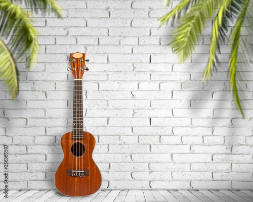 Ukulele guitar on a white wall background. Concept of travel and lifestyle. © YB