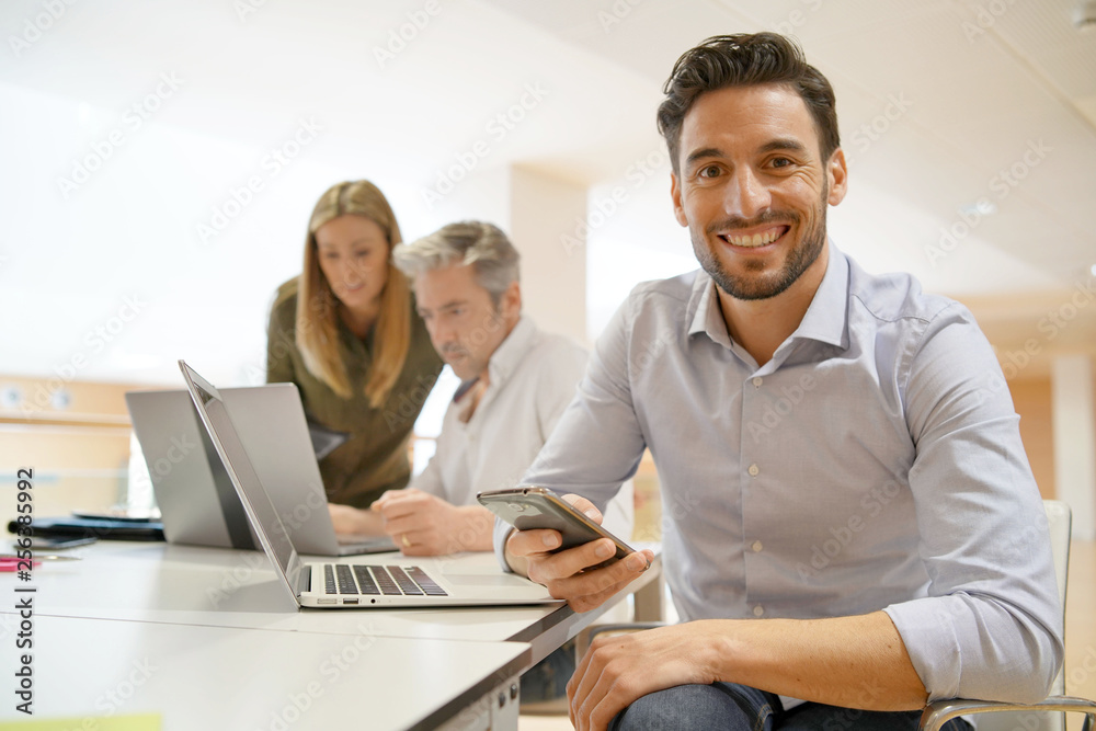 Startup team member smiling at camera in office Startup team member smiling at camera in office