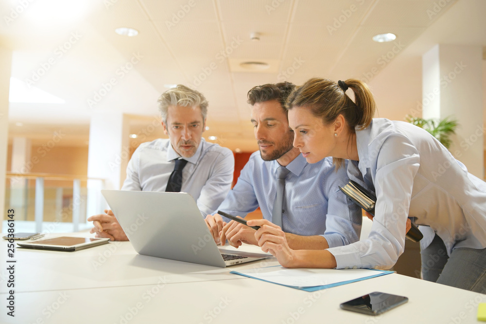 Group of startup coworkers looking at computer in office Group of startup coworkers looking at computer in office