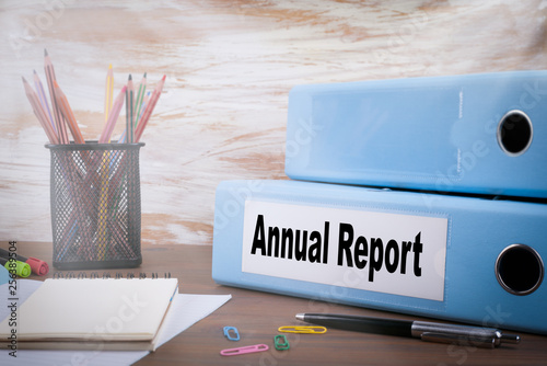Annual Report, Office Binder on Wooden Desk. On the table colored pencils, pen, notebook paper