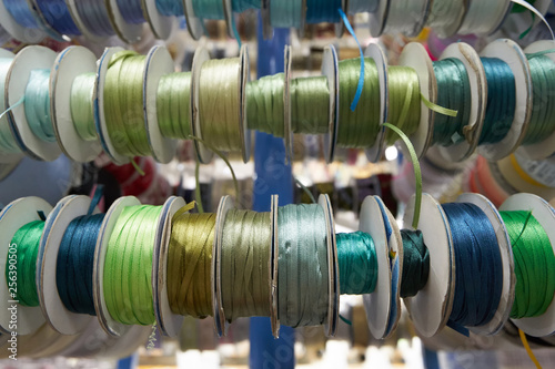 Colored ribbons for needlework in coils on the shelf in store. Close-up