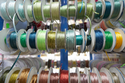 Colored ribbons for needlework in coils on the shelf in store. Close-up
