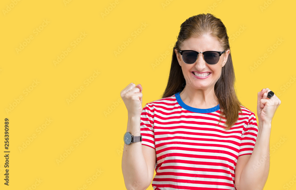 Middle age mature woman wearing sunglasses over isolated background celebrating surprised and amazed for success with arms raised and open eyes. Winner concept. Middle age mature woman wearing sunglasses over isolated background celebrating surprised and amazed for success with arms raised and open eyes. Winner concept.