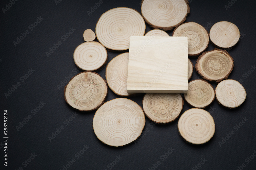 Pine tree cross-sections with annual rings and wooden square onblack surface. Lumber piece close-up shot, top view. Pine tree cross-sections with annual rings and wooden square onblack surface. Lumber piece close-up shot, top view.