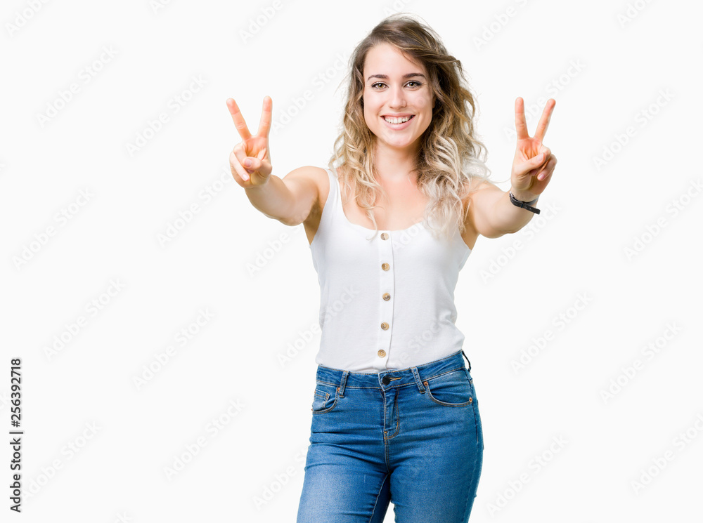 Young beautiful blonde woman over isolated background smiling looking to the camera showing fingers doing victory sign. Number two.