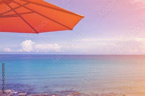 Orange beach umbrella on a sunny day, sea in background. Orange umbrella spread on the beach in summer season.