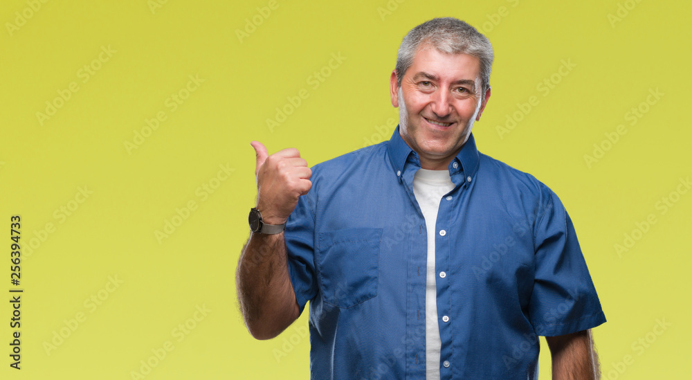 Handsome senior man over isolated background smiling with happy face looking and pointing to the side with thumb up.