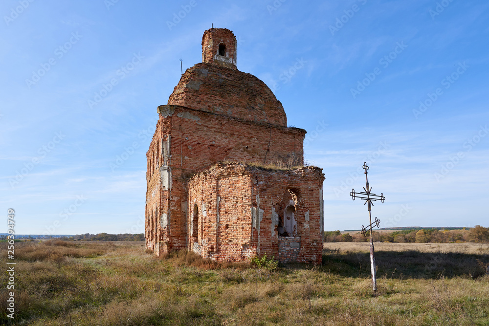 Old destroyed and abandoned church against the blue sky, in the middle of the field