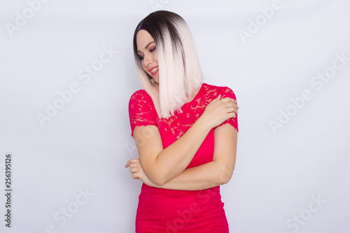 Young blonde woman over white background in bright pink dress