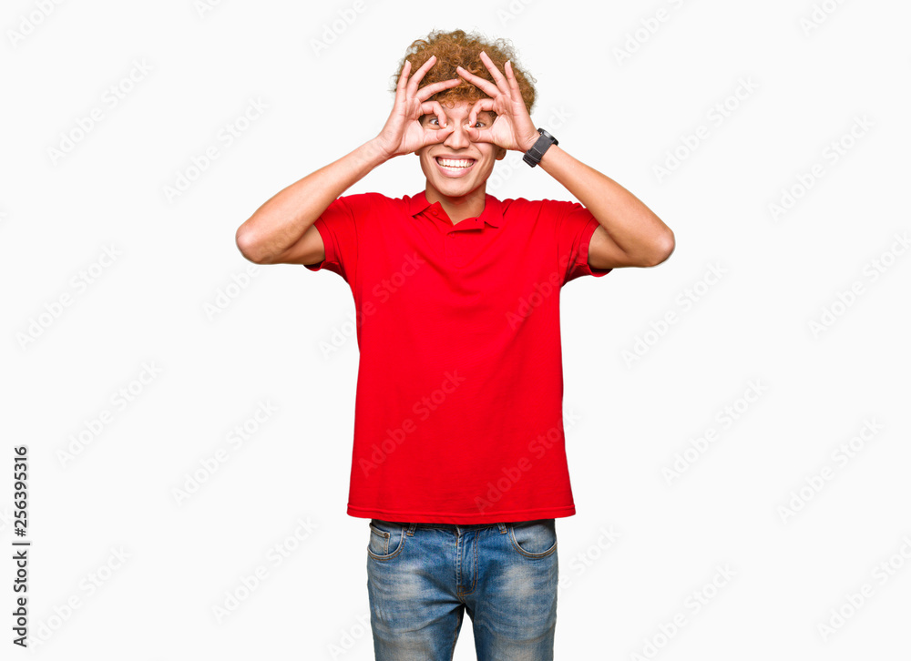 Young handsome man with afro hair wearing red t-shirt doing ok gesture like binoculars sticking tongue out, eyes looking through fingers. Crazy expression. Young handsome man with afro hair wearing red t-shirt doing ok gesture like binoculars sticking tongue out, eyes looking through fingers. Crazy expression.