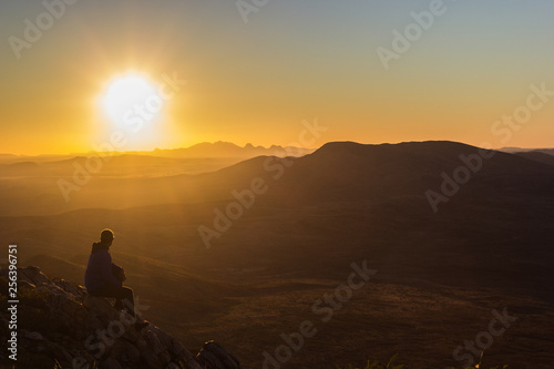 man enjoying sunset after a hike to the top of Mount Sonder just outside Alice Springs, West MacDonnel National Park, Australia
