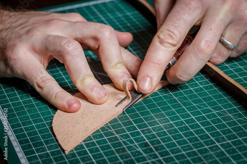 A person working as an artisan in his leather workshop removes the chamfer