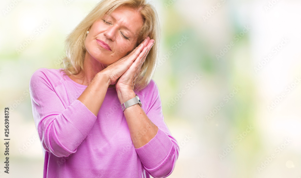 Middle age blonde woman over isolated background sleeping tired dreaming and posing with hands together while smiling with closed eyes. Middle age blonde woman over isolated background sleeping tired dreaming and posing with hands together while smiling with closed eyes.