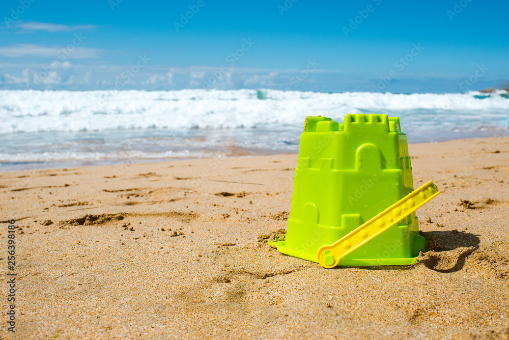 Green plastic bucket on a beach, summer holiday concept Green plastic bucket on a beach, summer holiday concept