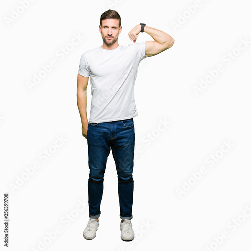 Handsome man wearing casual white t-shirt Strong person showing arm muscle, confident and proud of power