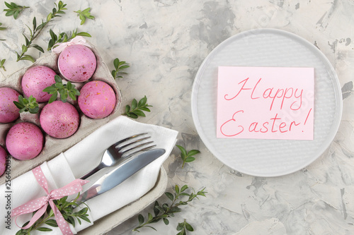 Easter. Pink Easter eggs and a knife with a fork and a plate on a light concrete background. Easter table setting. Happy easter. holidays. top view.