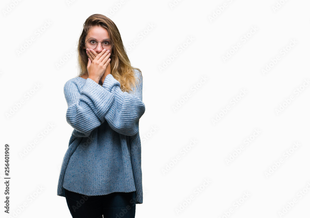 Young beautiful blonde woman wearing sweater and glasses over isolated background shocked covering mouth with hands for mistake. Secret concept. Young beautiful blonde woman wearing sweater and glasses over isolated background shocked covering mouth with hands for mistake. Secret concept.